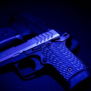 A striking close-up of two pistols illuminated by blue UV light, emphasizing texture and detail.