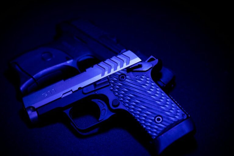 A striking close-up of two pistols illuminated by blue UV light, emphasizing texture and detail.