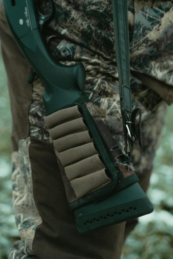 Close-up of a rifle with ammunition holder and camouflage clothing, perfect for hunting themes.