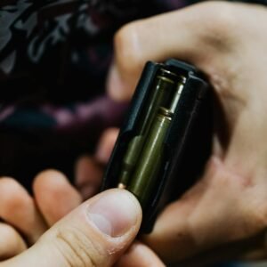Detailed close-up of hands loading bullets into a rifle magazine, emphasizing focus and precision.