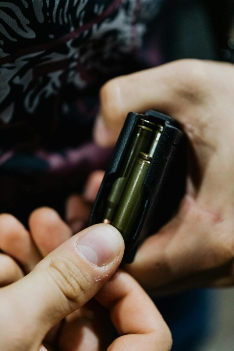 Detailed close-up of hands loading bullets into a rifle magazine, emphasizing focus and precision.